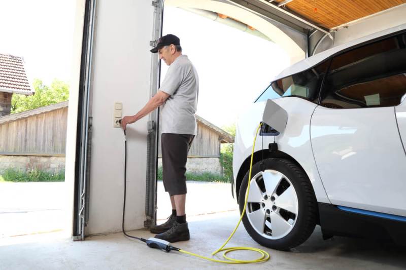Man charging EV in garage