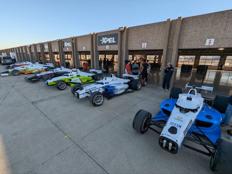 A line of race cars outside a building.