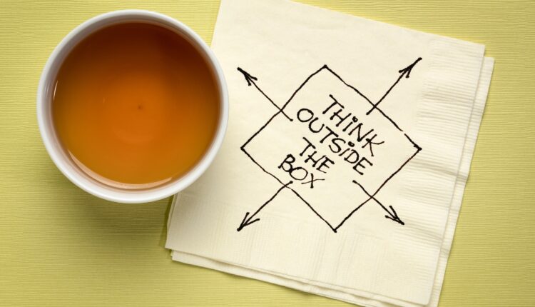 "think outside the box" written on a white napkin against a green background.
