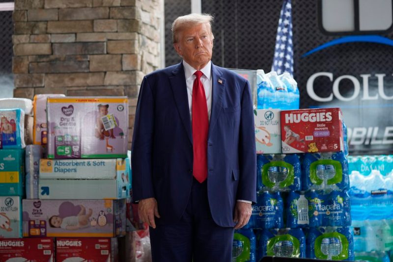 Republican presidential nominee former President Donald Trump listens as Georgia Gov. Brian Kemp speaks at a temporary relief shelter as he visits areas impacted by Hurricane Helene, Friday, Oct. 4, 2024, in Evans, Ga. (AP Photo/Evan Vucci)