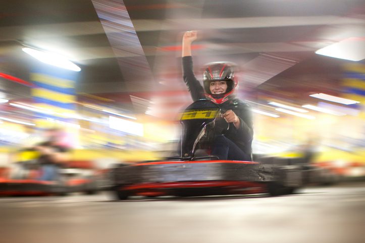 Mid adult woman driving indoor go-kart