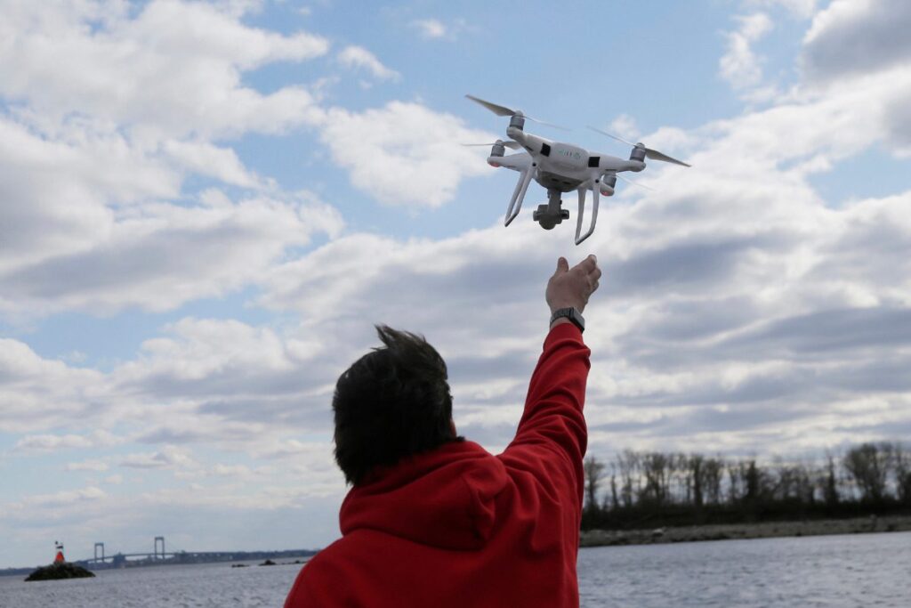 FILE - In this April 29, 2018, file photo, a drone operator helps to retrieve a drone after photographing over Hart Island in New York. (AP Photo/Seth Wenig, File)