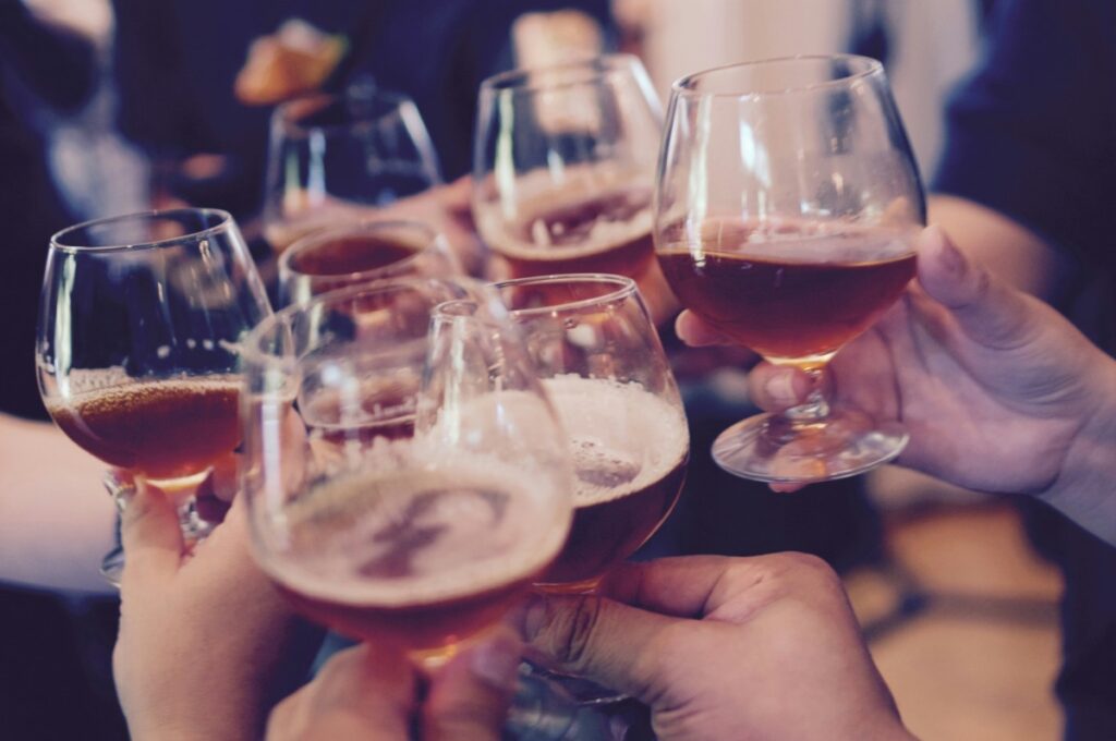 A group of hands toasting glasses of beer at a brewery