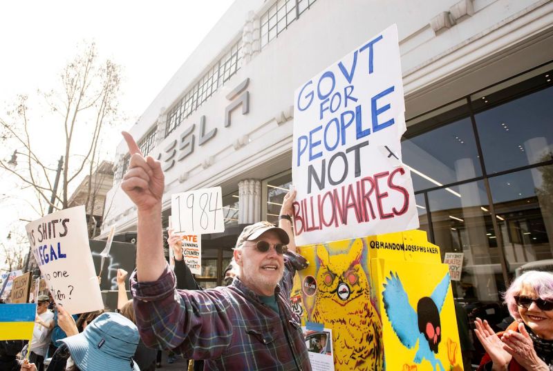 Mark Crosley holds up a sign and yells during a protest outside a Tesla dealership in San Francisco, Saturday, March 15, 2025.