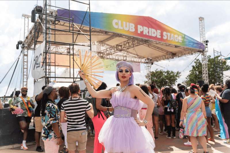 A drag queen in lavender in front of a crowd