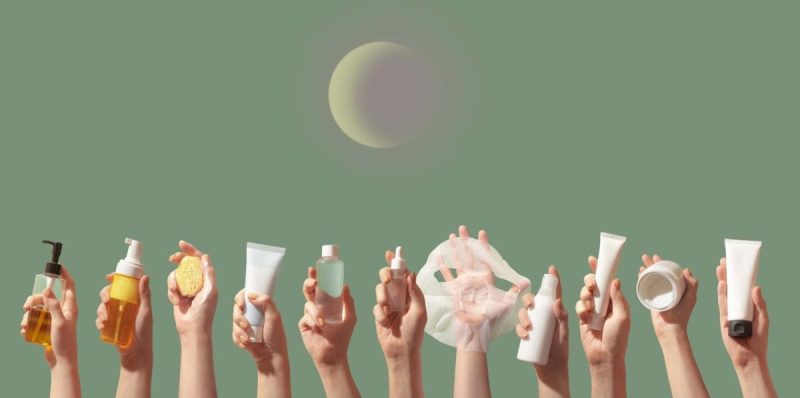 Hands holding multiple k-beauty products against green background