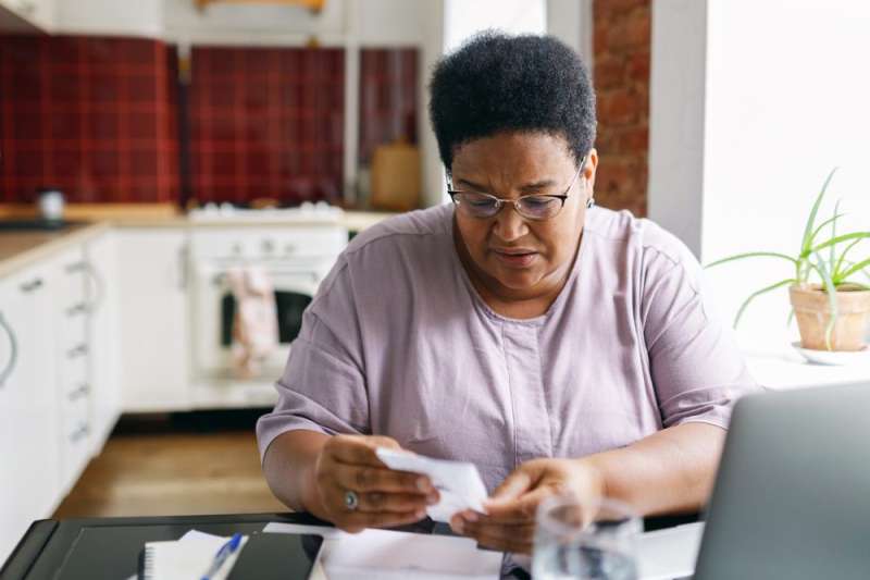 Photo of senior citizen woman looking worried while reviewing utility bills to be paid.