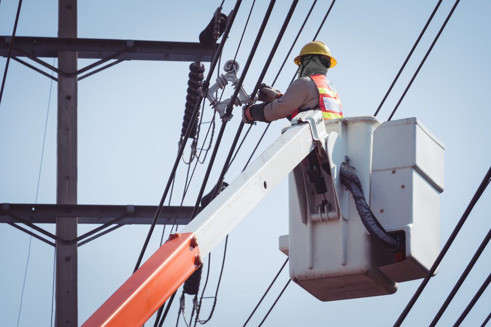 Photo of a man in a lifter working on a power line.