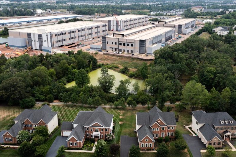 STONE RIDGE, VIRGINIA - JULY 17: In an aerial view, an Amazon Web Services data center is shown situated near single-family homes on July 17, 2024 in Stone Ridge, Virginia. Northern Virginia is the largest data center market in the world, according to a report this year cited in published accounts, but is facing headwinds from availability of land and electric power.