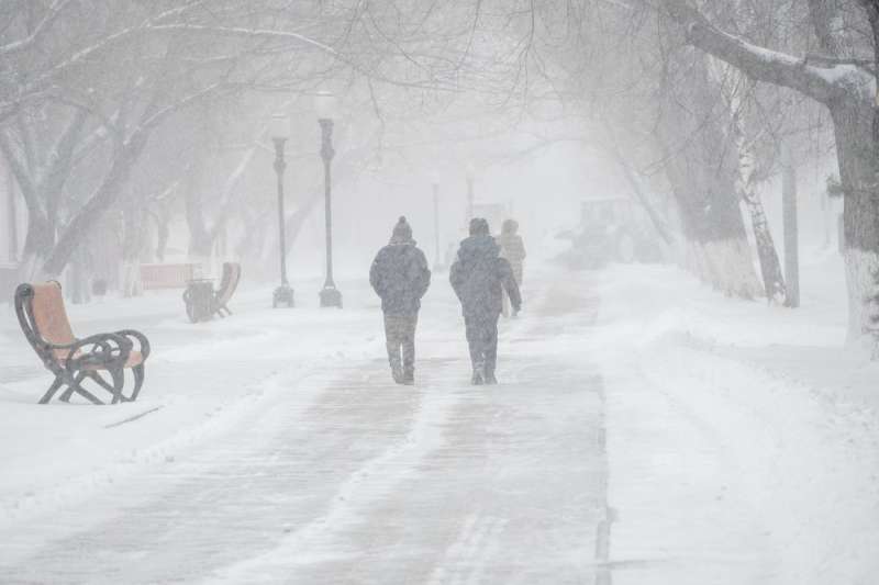 Photo of two people walking in the middle of a snow storm.