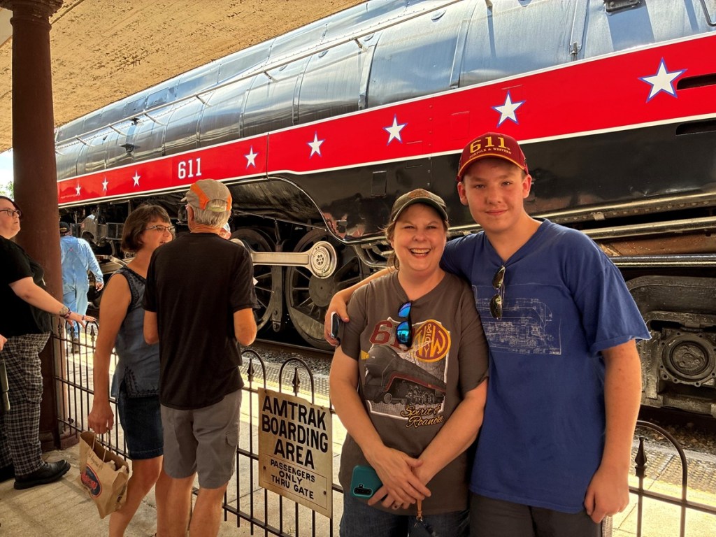 Two people pose in front of a train