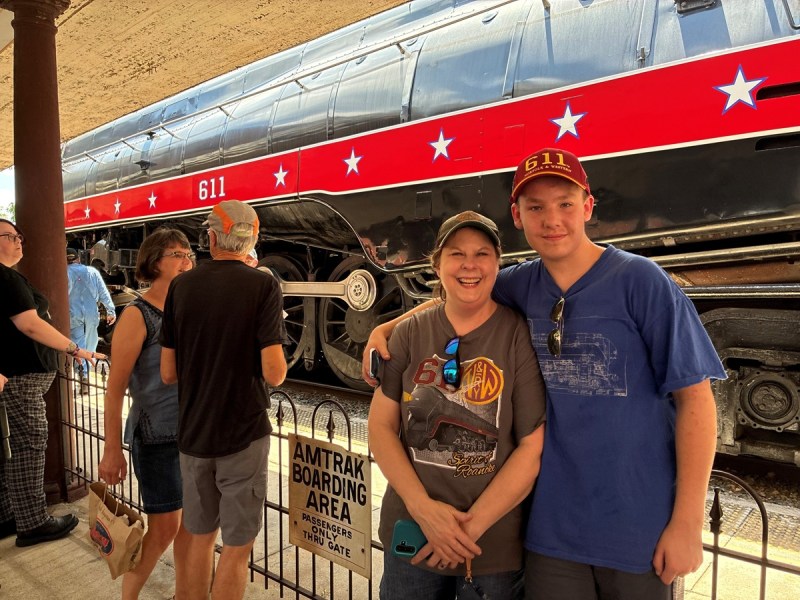 Two people pose in front of a train