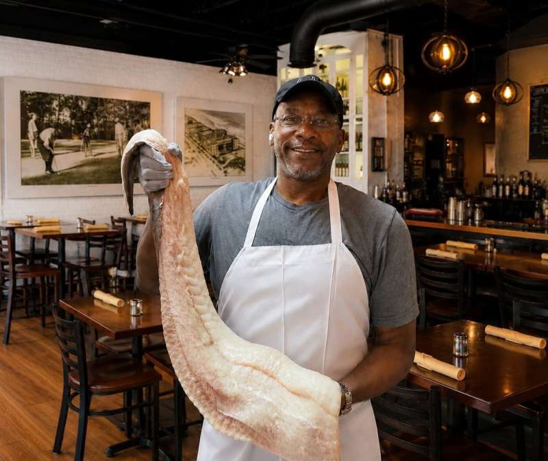 Alvin Williams holds a huge piece of fish in one of the Black-owned restaurants in Virginia