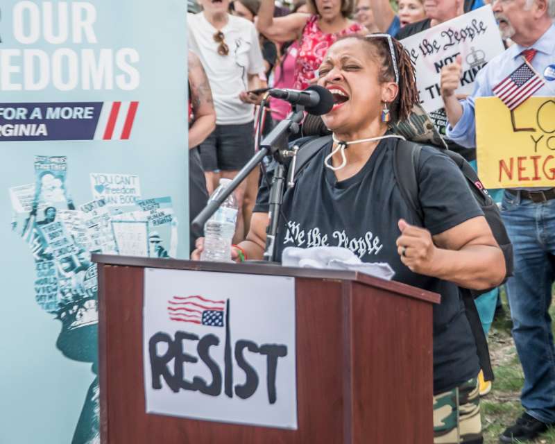 Black woman stands in front of crowd at a podium speaking about the abortion amendment