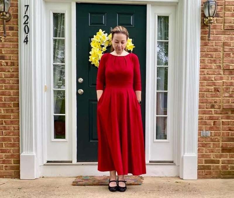Adelle LaRue Settle standing in front of a door wearing a red dress to express her stance on Virginia Question 1